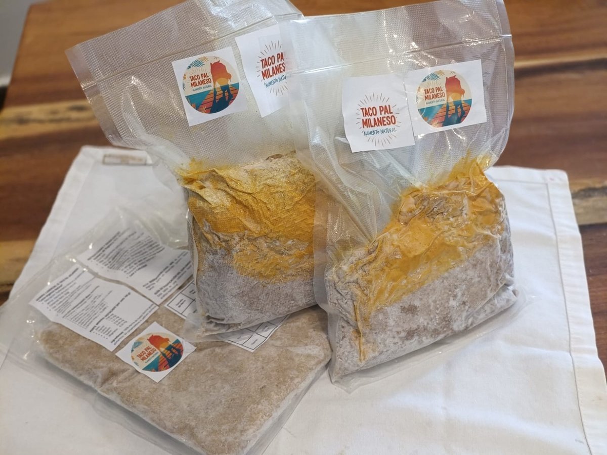 Cuatro paquetes de tortillas o suplementos en bolsas de plástico con logos coloridos, acomodados sobre papel blanco en una superficie de madera